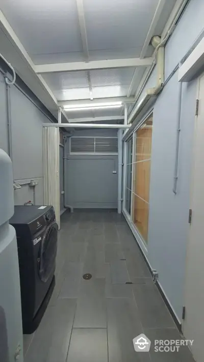 Spacious laundry area with modern washing machine and sleek tiled flooring