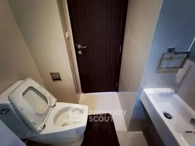 Modern bathroom with sleek fixtures and minimalist design, featuring a toilet and compact sink.