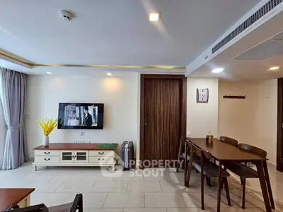 Modern living room with dining area, wall-mounted TV, and stylish furniture