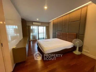 Spacious modern bedroom with wooden flooring and balcony access