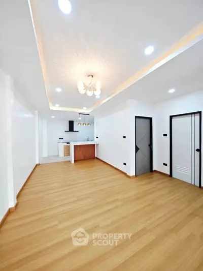 Spacious modern living room with open kitchen and elegant lighting, featuring sleek wooden flooring and contemporary design.