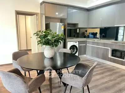 Modern kitchen with sleek cabinetry, dining table, and built-in appliances in a stylish apartment.