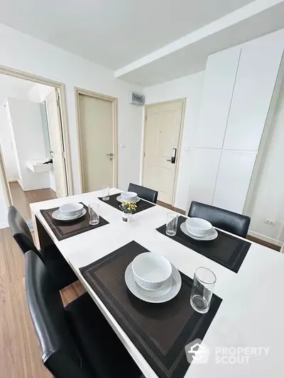 Modern dining area with sleek black chairs and white table set for four in a stylish apartment.