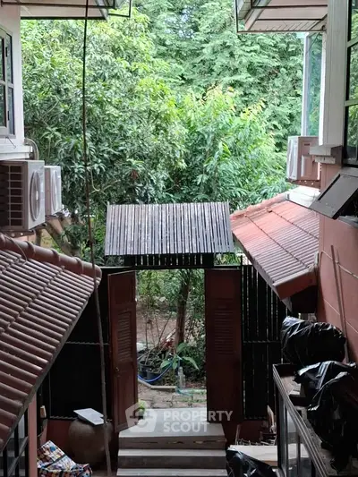 Charming residential entrance with lush greenery and traditional architectural elements.