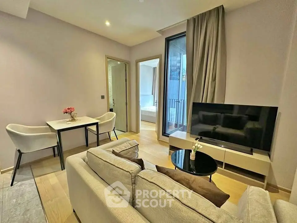 Modern living room with cozy seating and large TV, adjacent to dining area and bedroom.