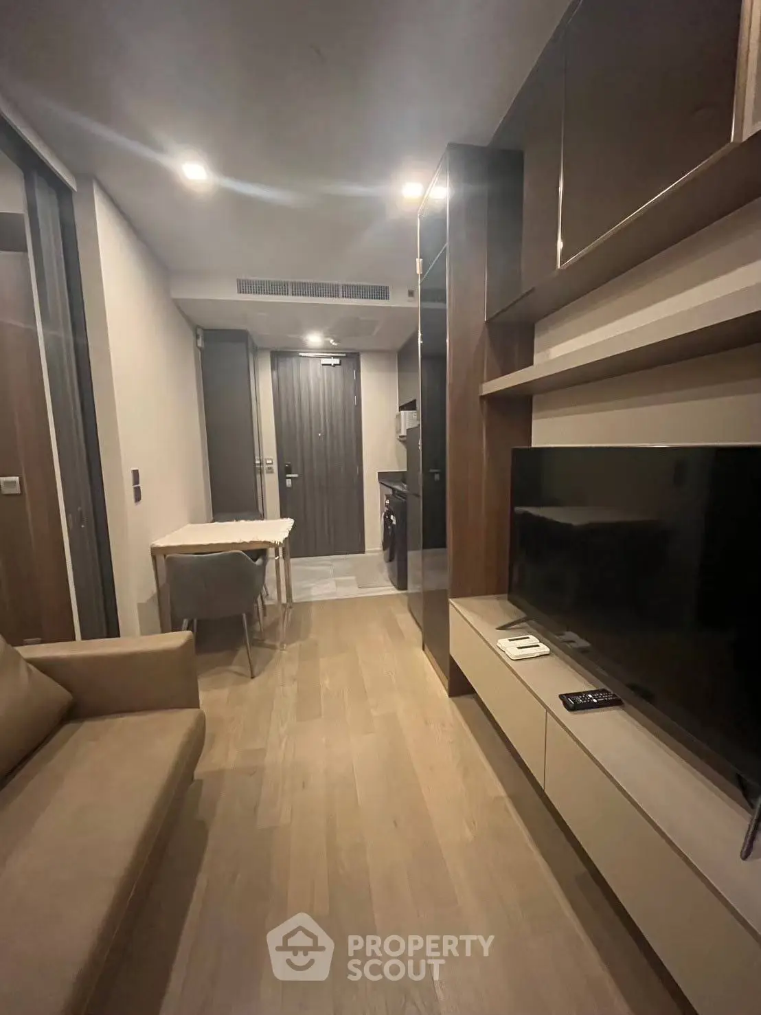 Modern living room with sleek furniture and integrated TV unit in a cozy apartment.