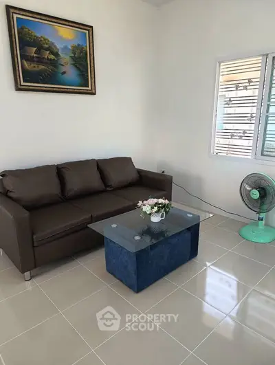 Cozy living room with brown sofa, glass coffee table, and wall art in a bright space.