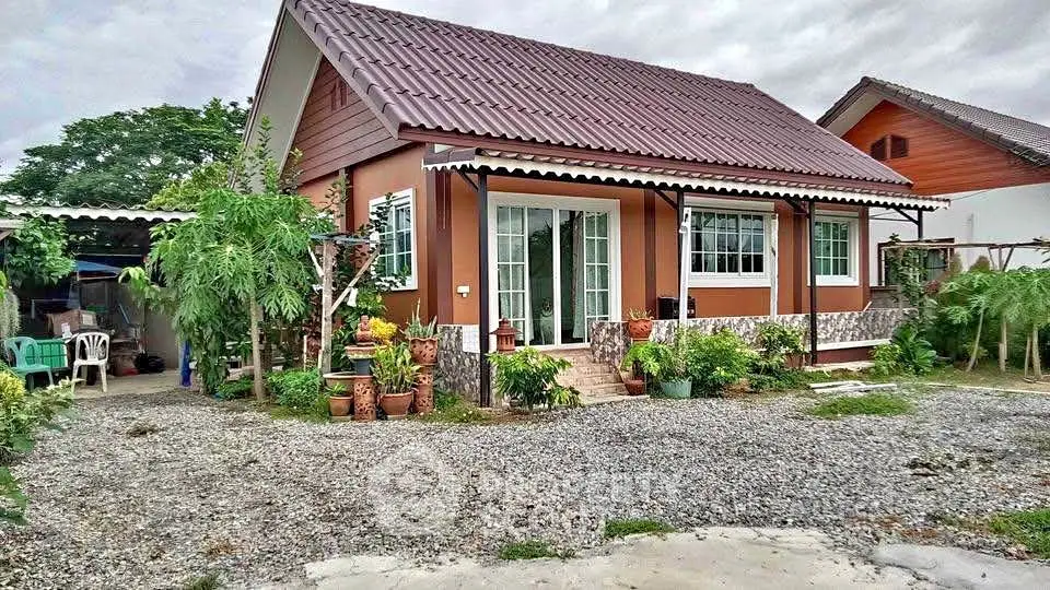 Charming single-story house with lush garden and spacious gravel driveway.