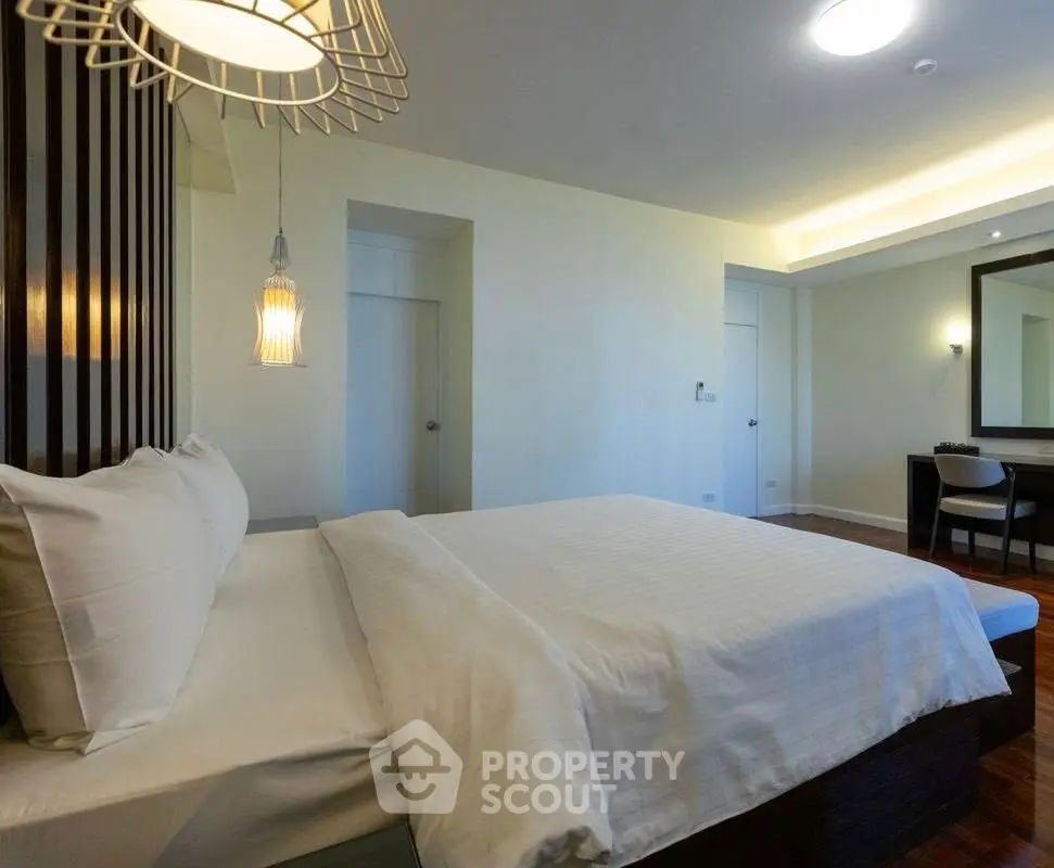 Spacious modern bedroom with elegant lighting and cozy ambiance.