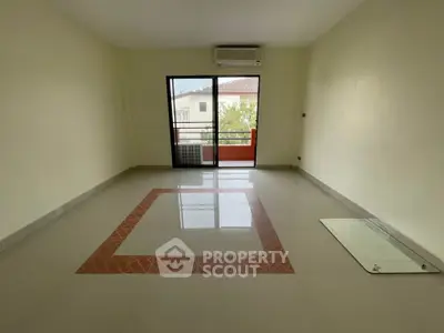 Spacious empty living room with balcony access and air conditioning.