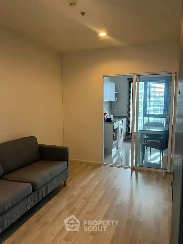 Modern apartment with cozy living room and sleek kitchen featuring washing machine and dining area.