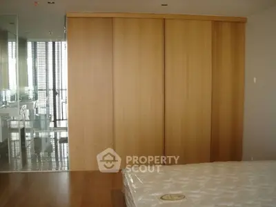 Spacious bedroom with wooden flooring and large built-in wardrobe, offering modern and sleek design.