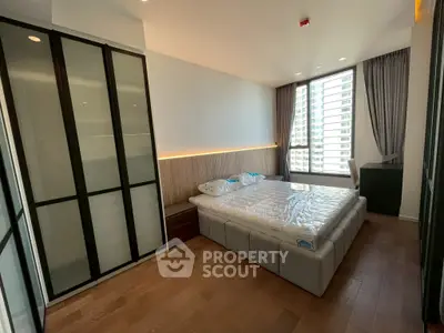 Modern bedroom with large window and stylish lighting in urban apartment.