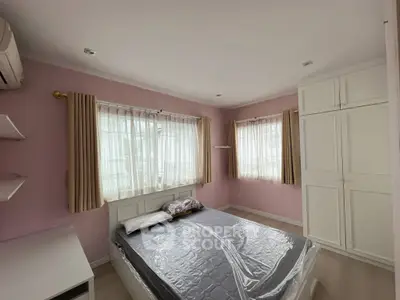 Cozy bedroom with pink walls, large windows, and ample storage in a modern home.