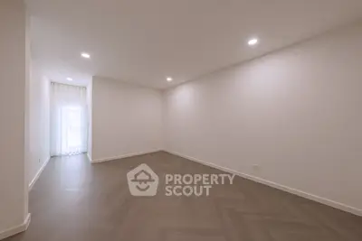 Spacious empty room with elegant herringbone flooring and soft lighting.