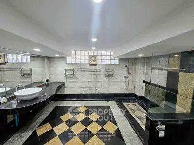 Luxurious modern bathroom with elegant black and gold tile design, featuring a spacious shower area and stylish sink.