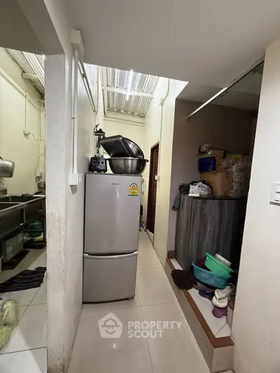 Compact kitchen area with refrigerator and storage space in a cozy home setting.