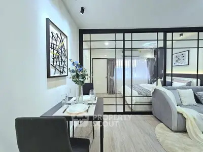 Modern open-plan living room with stylish decor and glass partition leading to a cozy bedroom.