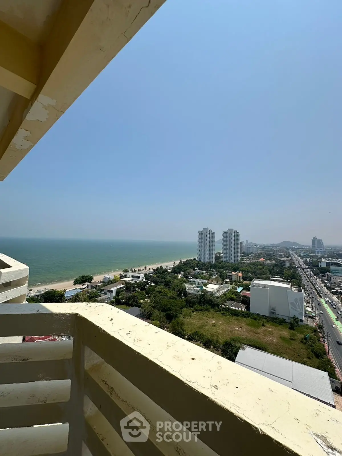 Stunning coastal view from high-rise balcony overlooking ocean and cityscape.