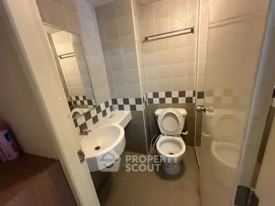 Compact bathroom with modern fixtures and tiled walls, featuring a toilet and sink.