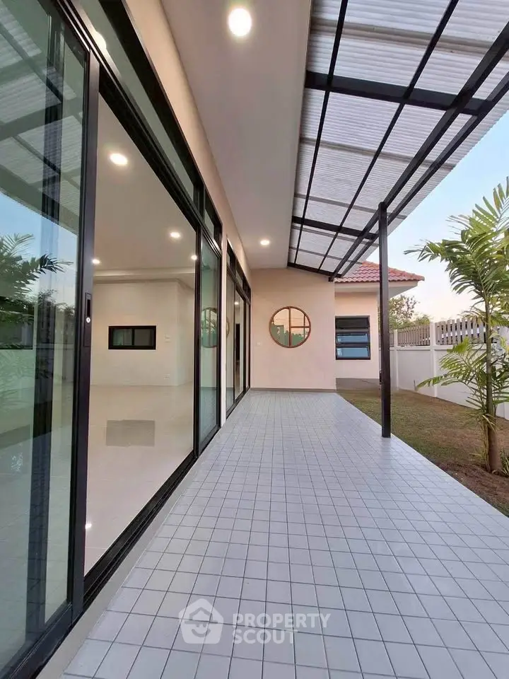 Modern home exterior with spacious tiled patio and large glass doors, perfect for indoor-outdoor living.