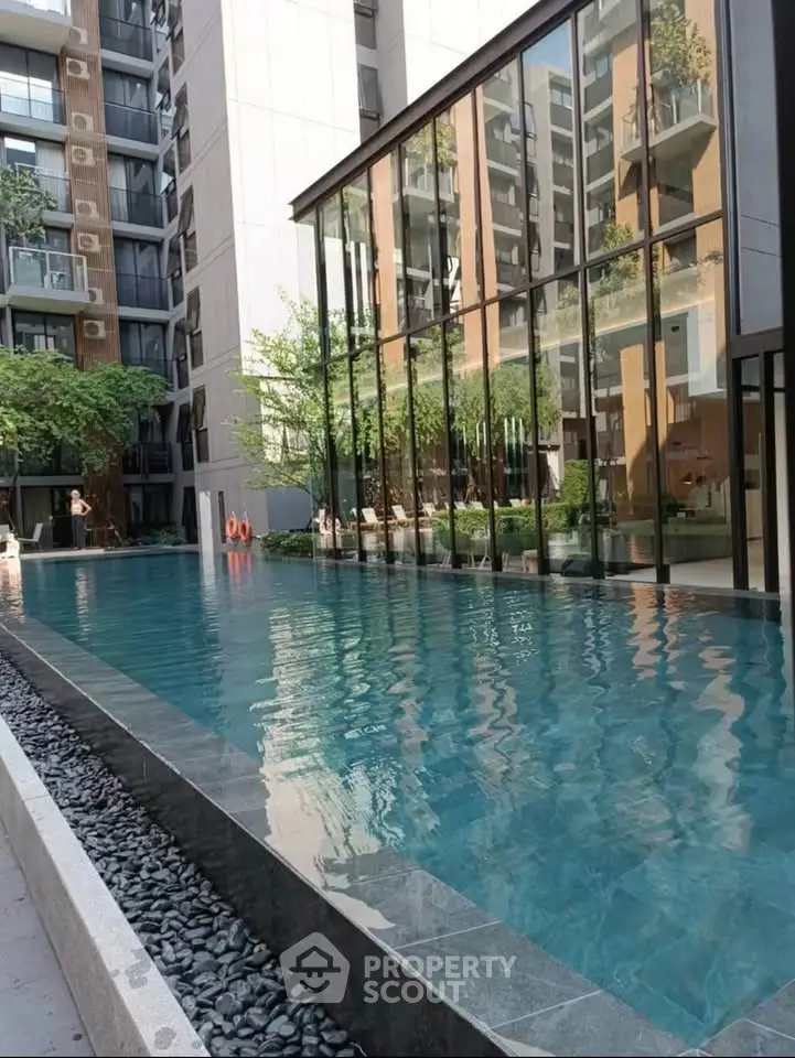 Luxurious modern apartment complex with stunning outdoor pool and sleek glass architecture.