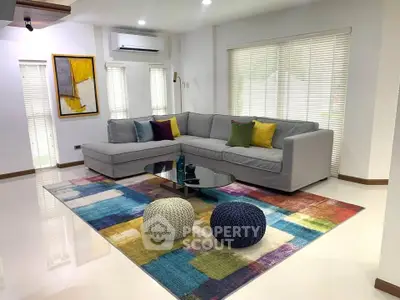Spacious living room with modern sectional sofa and colorful rug, perfect for relaxation.
