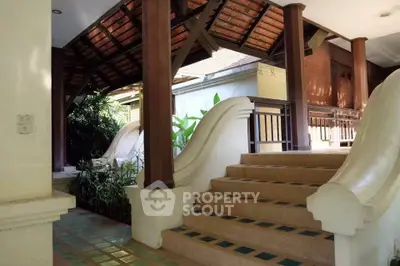 Charming tropical entrance with wooden beams and lush greenery