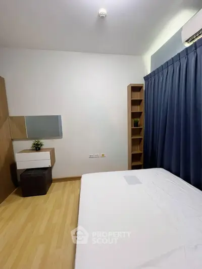 Modern bedroom with minimalist design, featuring wooden flooring, sleek furniture, and a large window with blue curtains.