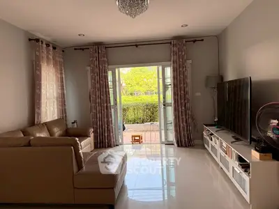 Spacious living room with large TV and garden view, perfect for relaxation.