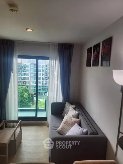 Cozy living room with modern decor and large window overlooking greenery.