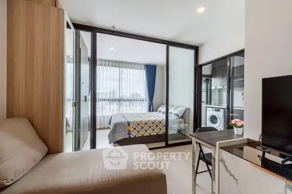 Modern studio apartment with glass partition, cozy living area, and washing machine.