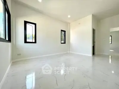 Spacious and bright empty room with modern white tile flooring and large windows.