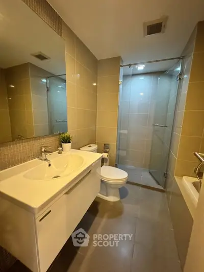 Modern bathroom with sleek fixtures and glass shower enclosure in a contemporary apartment.