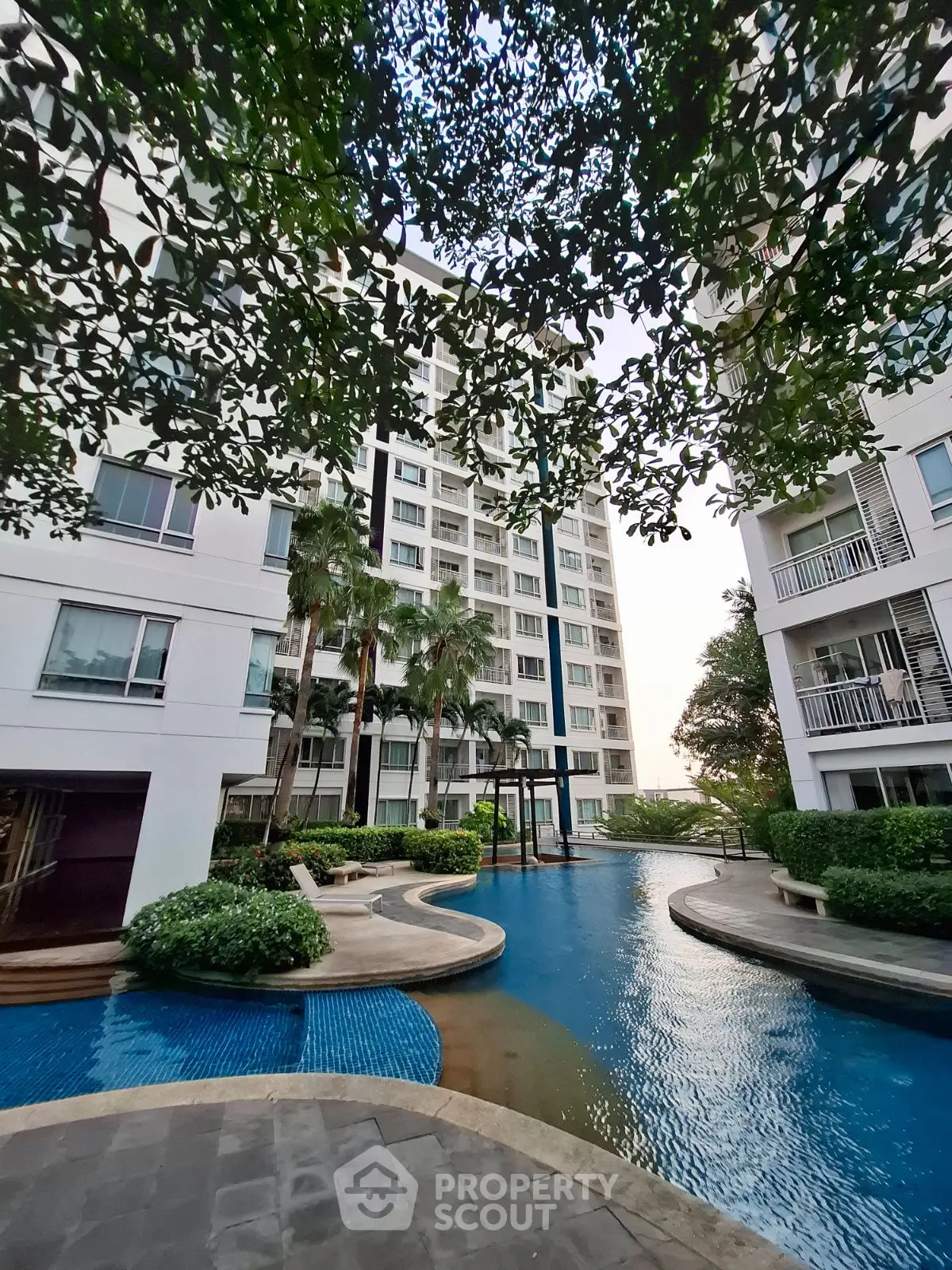 Luxurious apartment complex with serene pool and lush greenery