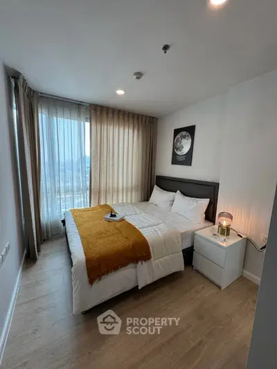 Modern bedroom with cozy decor and large window offering natural light