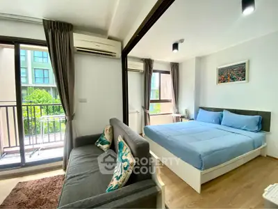 Modern studio apartment with balcony and stylish decor, featuring a cozy bed and comfortable seating area.