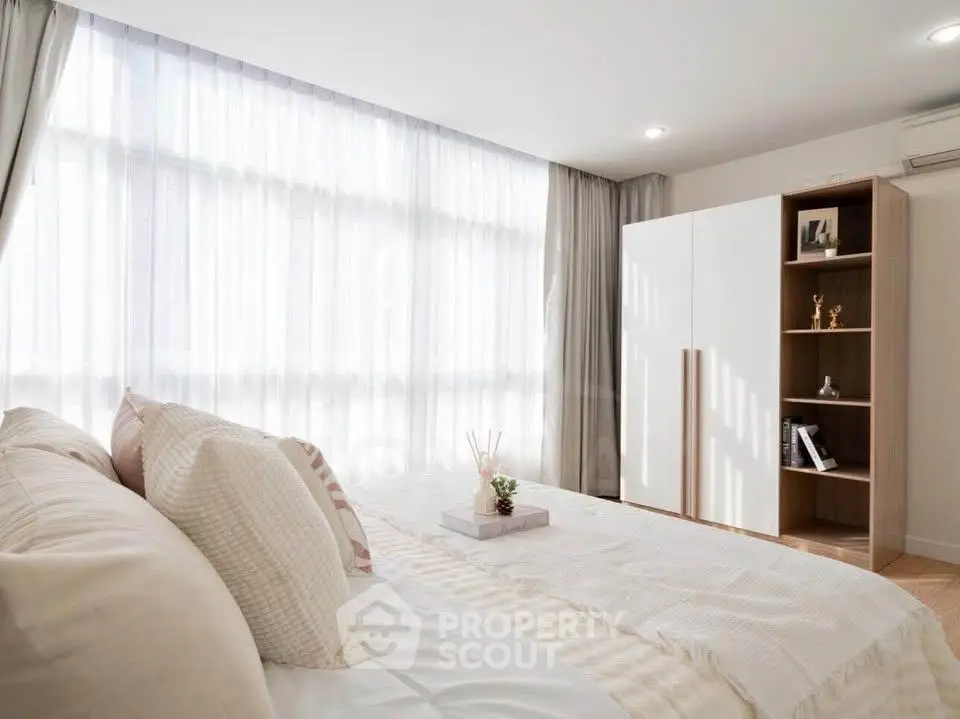 Bright and airy bedroom with modern decor and large window for natural light.