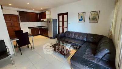 Spacious living room with modern kitchen and leather sofa in open layout apartment.