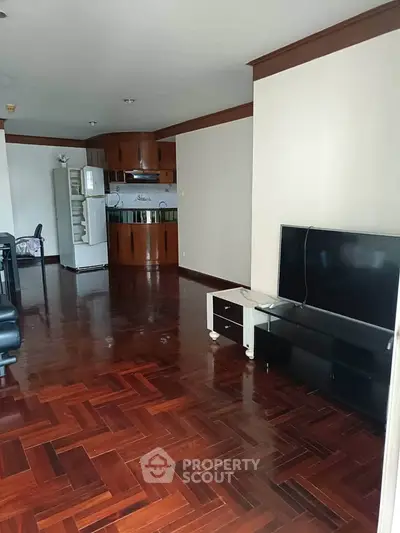 Spacious living room with hardwood floors and modern kitchen in open layout apartment.