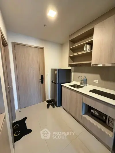 Modern compact kitchen with sleek cabinetry and built-in appliances in a cozy apartment.