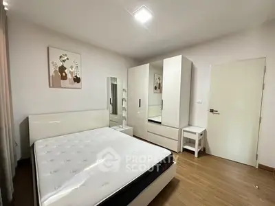 Modern bedroom with sleek white furniture and wooden flooring