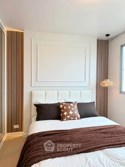 Modern bedroom with stylish decor and natural light, featuring a cozy bed and elegant wall paneling.
