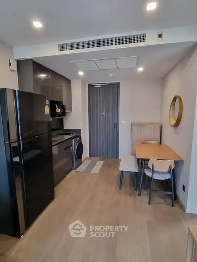 Modern kitchen with sleek appliances and dining area in stylish apartment.