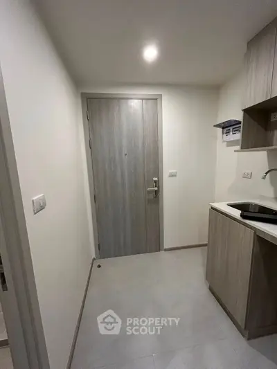 Compact modern apartment entrance with kitchenette, ideal for urban living.