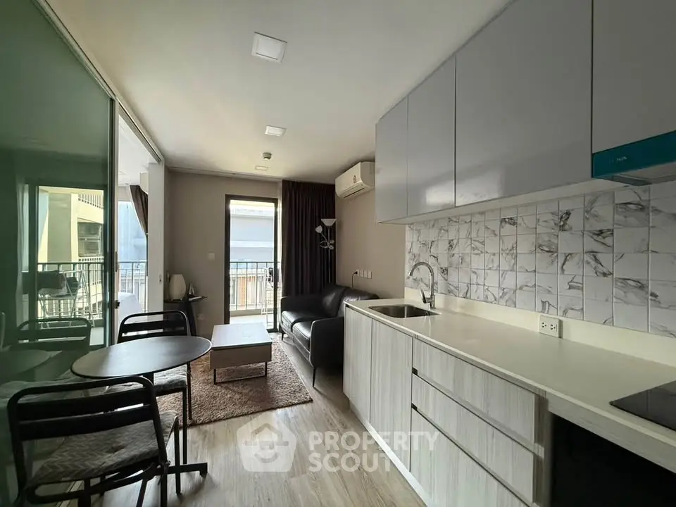 Modern open-layout living room with kitchen and balcony access in stylish apartment