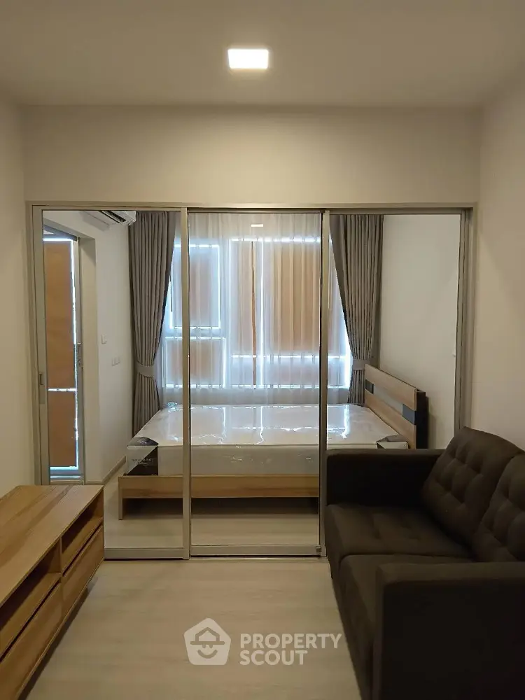 Modern bedroom with glass sliding doors and cozy sofa in stylish apartment