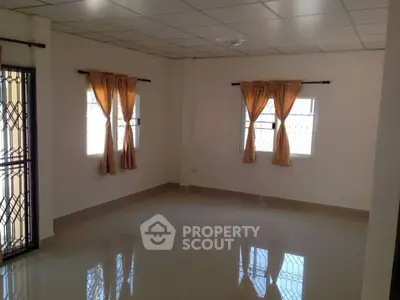Spacious empty room with tiled floor and large windows, ideal for customization.