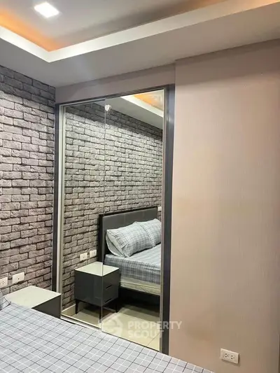 Modern bedroom with stylish brick accent wall and mirrored wardrobe