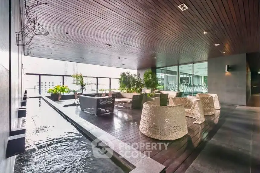 Luxurious rooftop lounge with modern seating and water feature in upscale building.